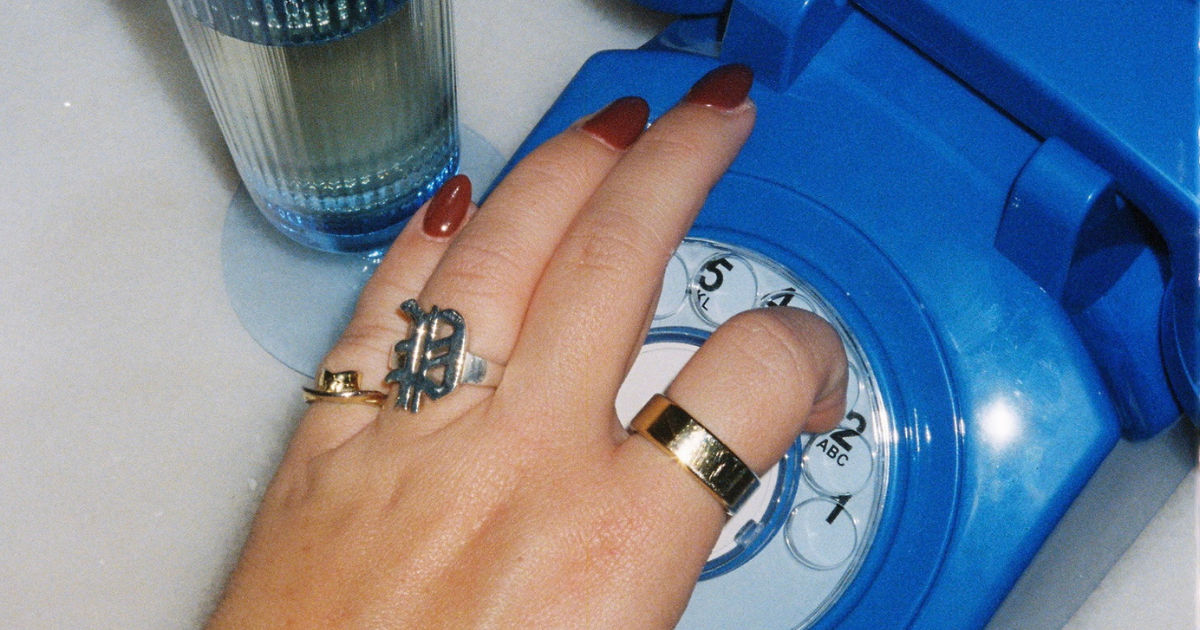 womans hand dialing on a blue rotary phone