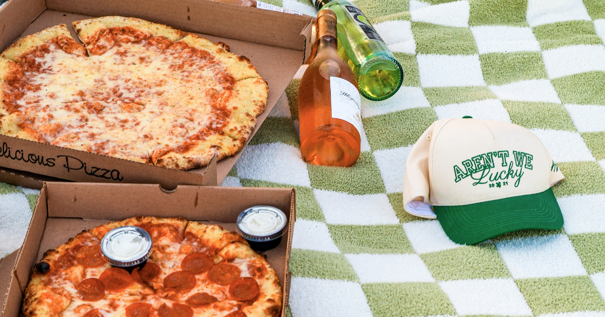 2 pizzas on a green and white checkered blanket